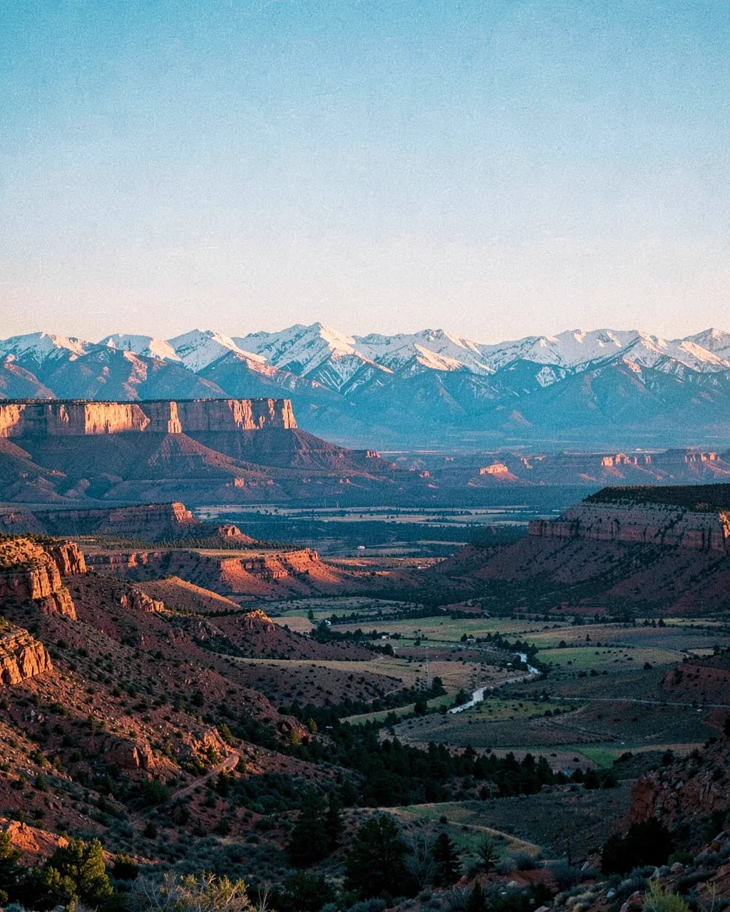 Wide Western Colorado landscape of mesas, ranchland and snow-capped peaks